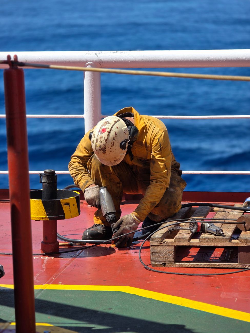 maritime worker performing maintenance on ship deck